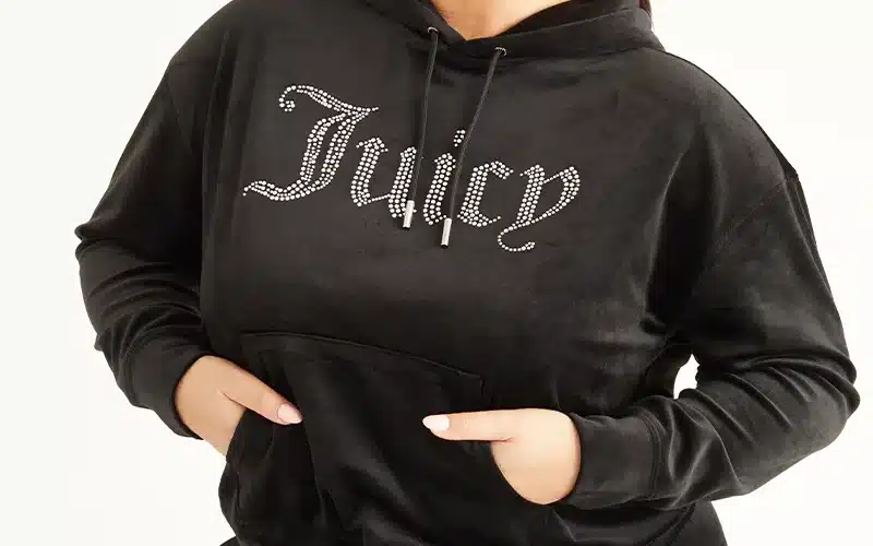 A woman wearing a black hoodie with the word juicy on it. black hoodie